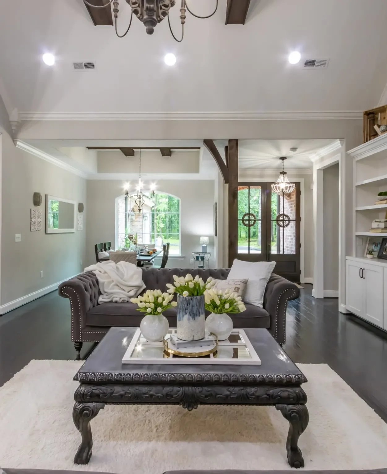 A Philadelphia living room with a couch and coffee table, decorated with a chandelier, vases of flowers, and a fireplace. 