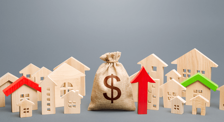 A collection of miniature wooden houses and a money bag with a dollar sign, accompanied by red and green arrows pointing upward, symbolizing an increase in value or investment.