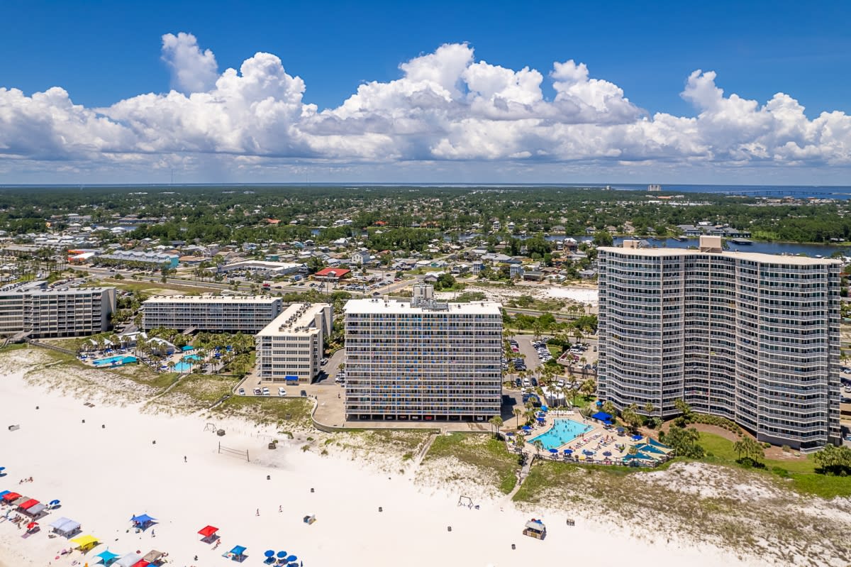 An aerial view of a large beachfront resort complex with multiple high-rise buildings. 