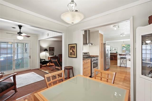 Dining area with a glass-top table opening onto a light-wood kitchen and living room.