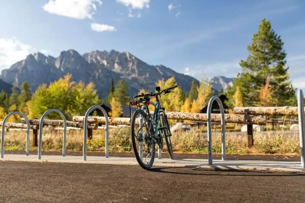 Scenic view of a cyclist riding along a trail in Jackson Hole, Wyoming, with the Teton Mountains in the background – highlighting outdoor activities near Jackson Hole real estate.