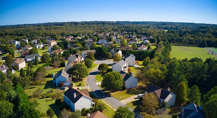  An aerial view of a suburban neighborhood with houses, trees, and green spaces.