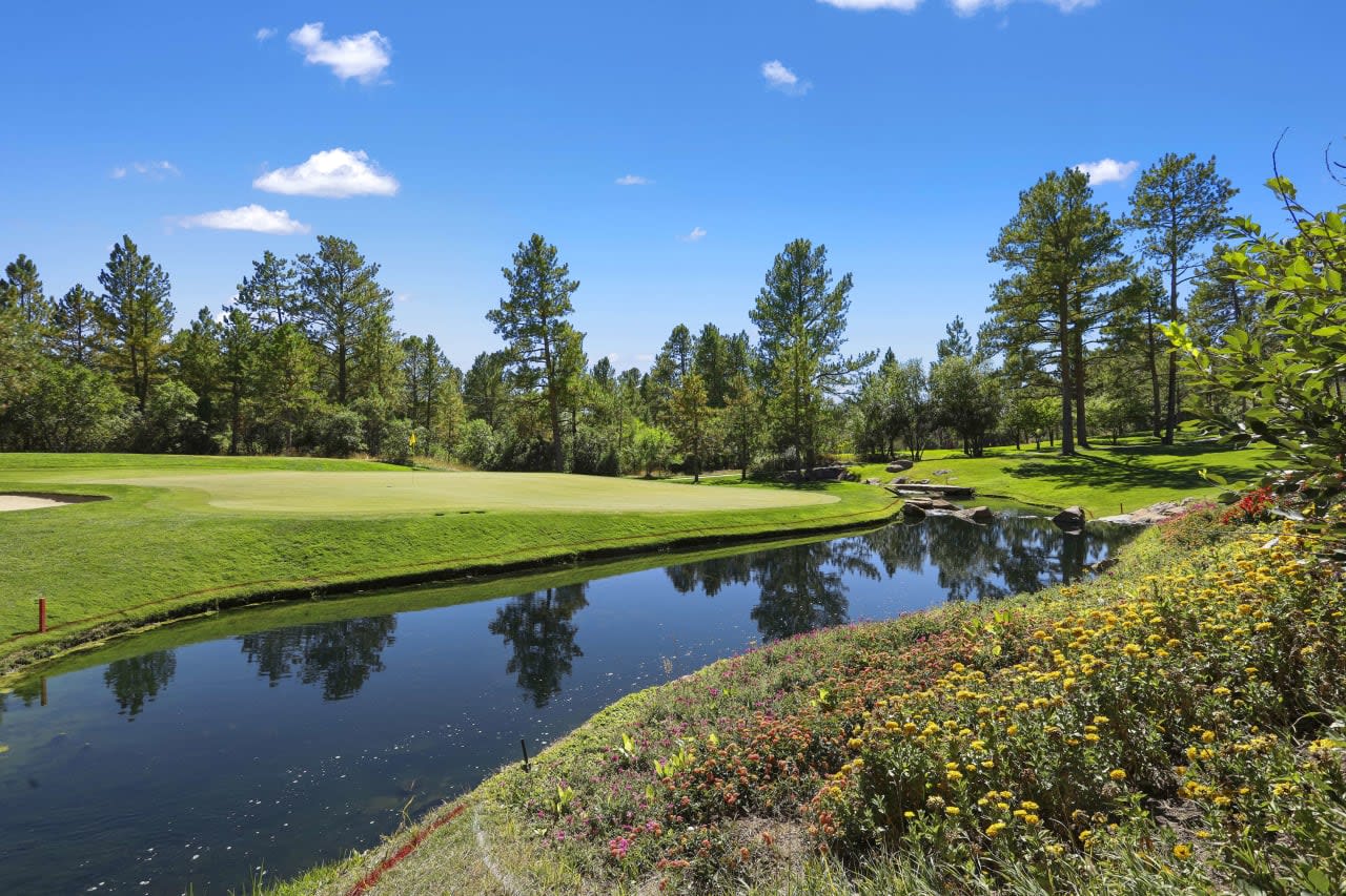 A picturesque pond surrounded by a vibrant golf course, radiating a peaceful ambiance.