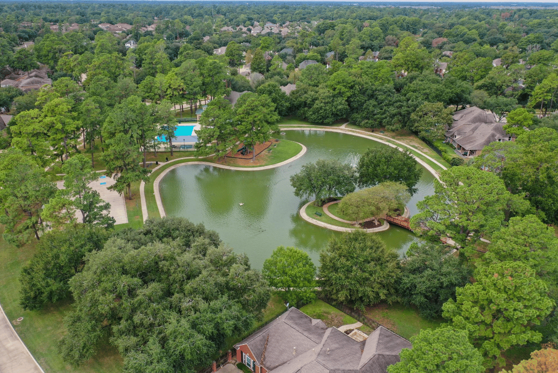 Aerial view of a neighborhood lake, walking paths, pool, and surrounding homes.