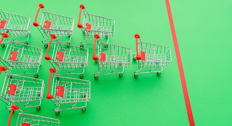 A row of shopping carts in a green background, which might be symbolic of consumer behavior or purchasing trends.