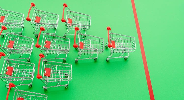 A row of shopping carts in a green background, which might be symbolic of consumer behavior or purchasing trends.