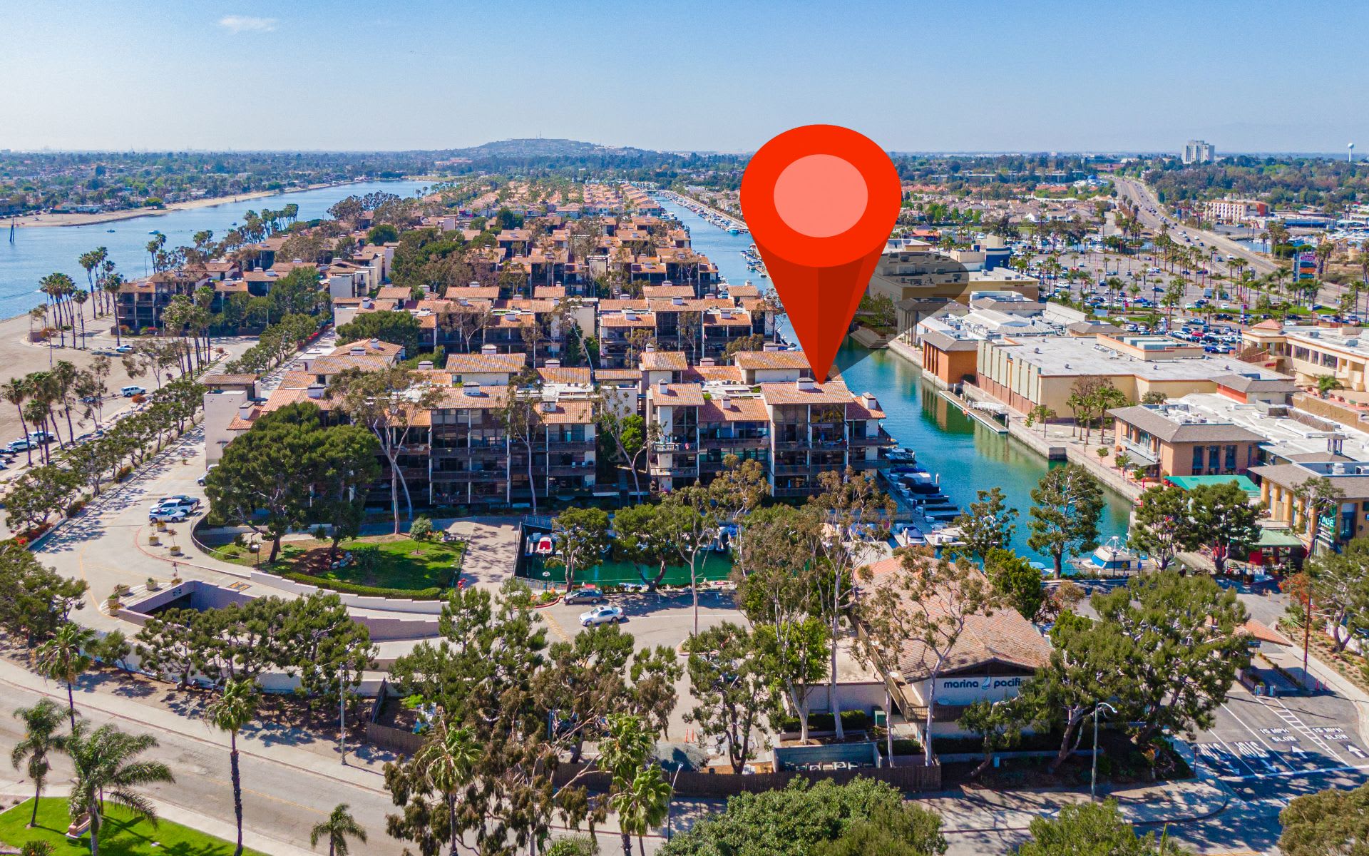 Aerial view of Marina Pacifica condominiums and canals, with a red location pin marking the property.