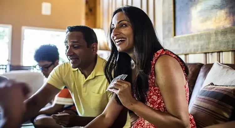 A man and a woman sitting together in a casual setting, possibly a café or a meeting. They are both smiling and engaged in conversation.