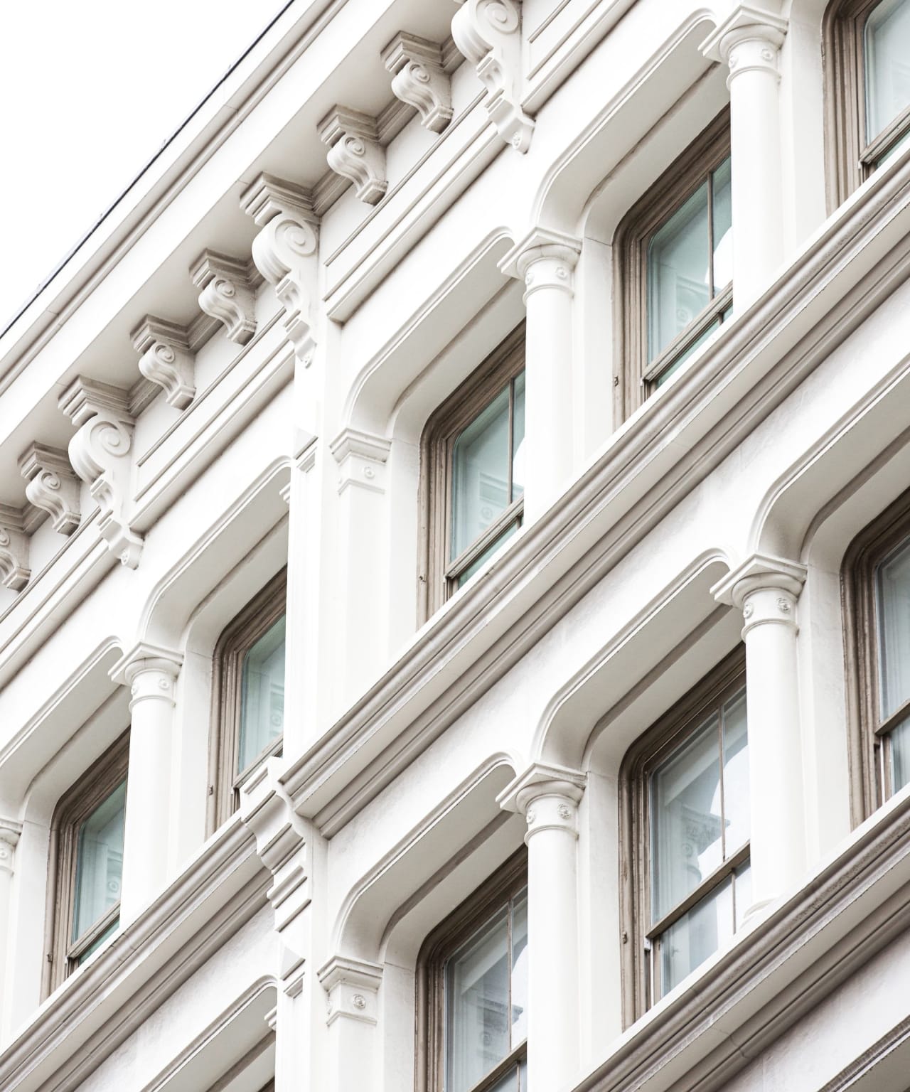 A low-angle shot of a classic, white brick building with ornate columns and tall windows.