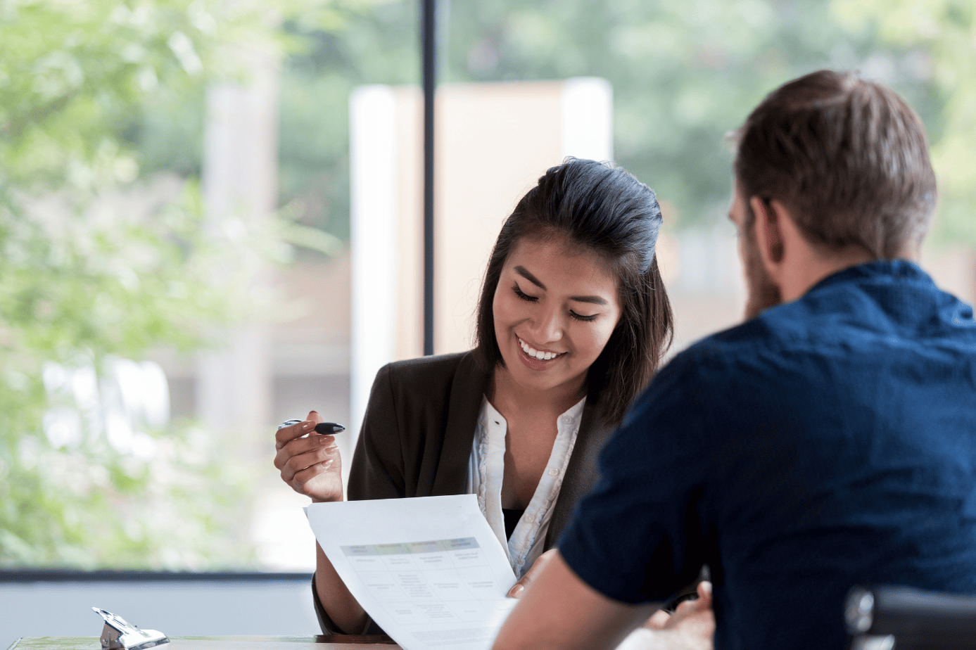 A woman reviews paperwork with a man during a consultation at a table.