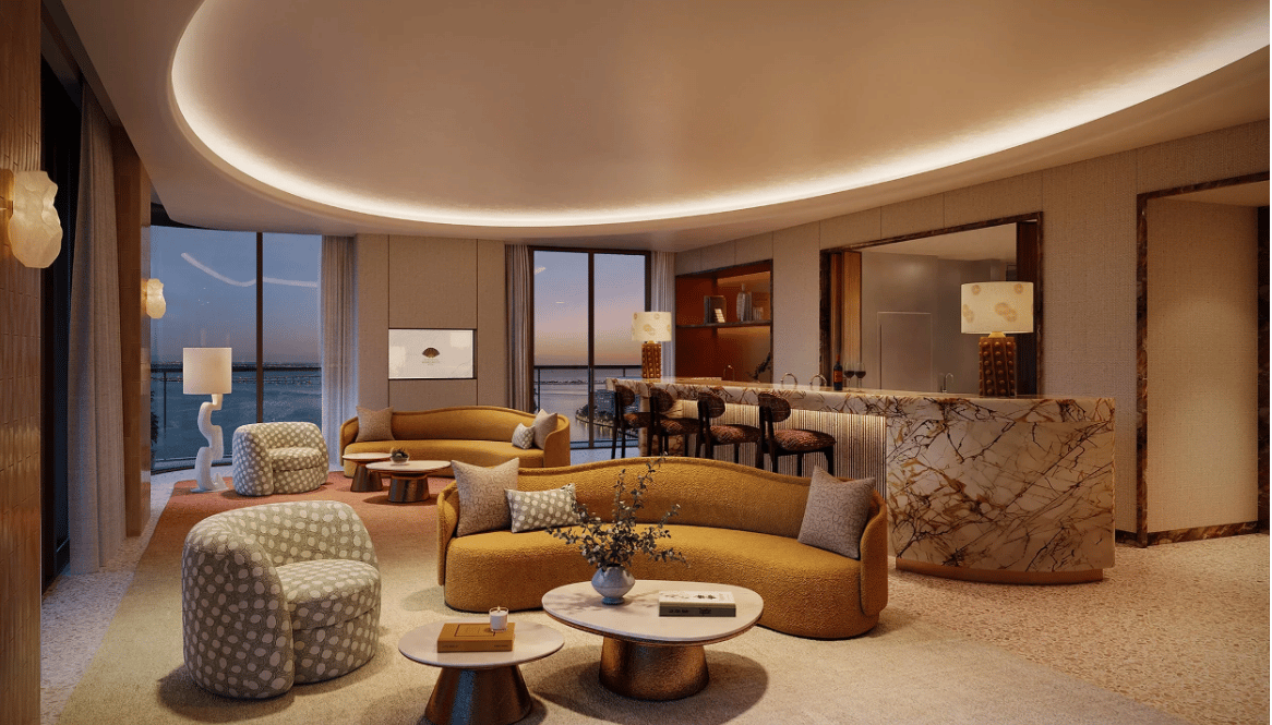 Luxury residence living room with curved mustard sofas and water views through floor-to-ceiling windows.