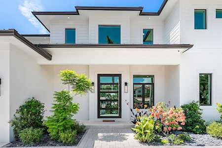Modern white two-story home with a glass entry and landscaped front walkway.