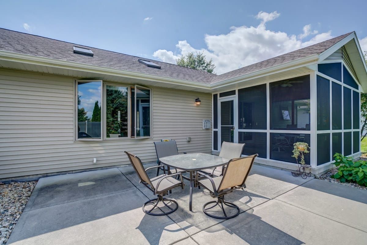 Rear patio with outdoor dining set beside a large screened-in porch.
