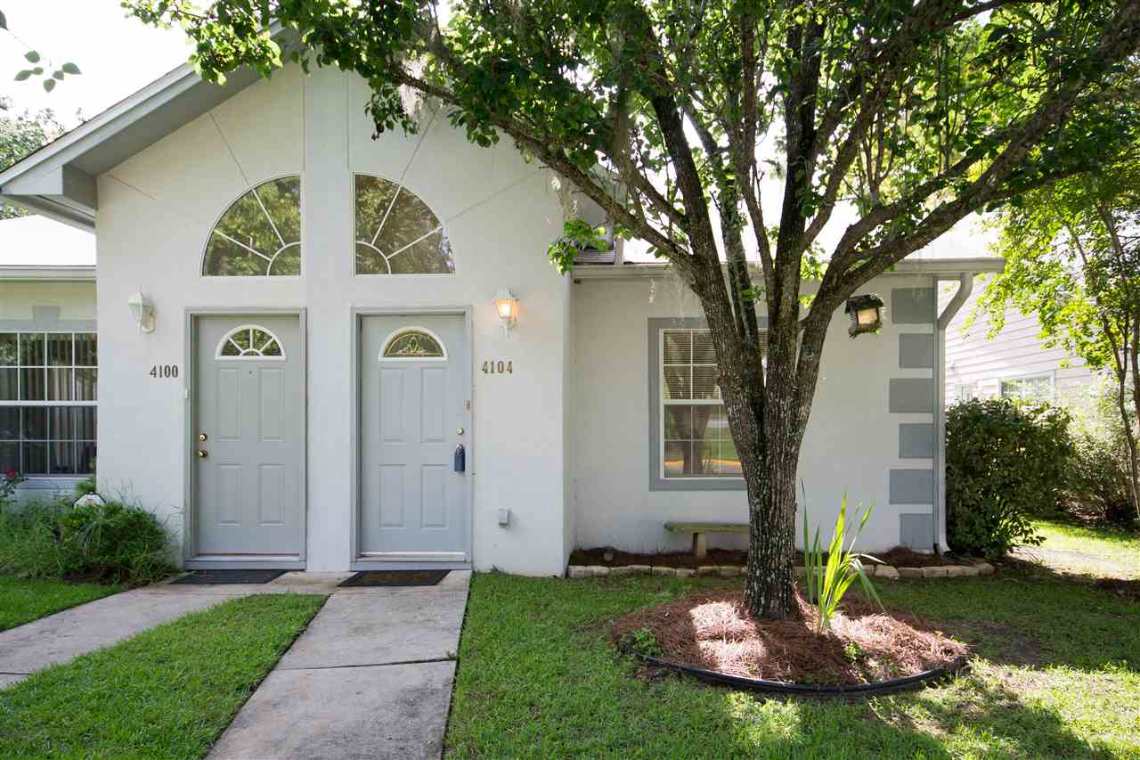 A cozy home featuring a welcoming front door beside a lush green tree in the yard.