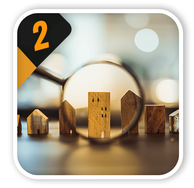 Wooden house models viewed through a magnifying glass, with an orange number 2.