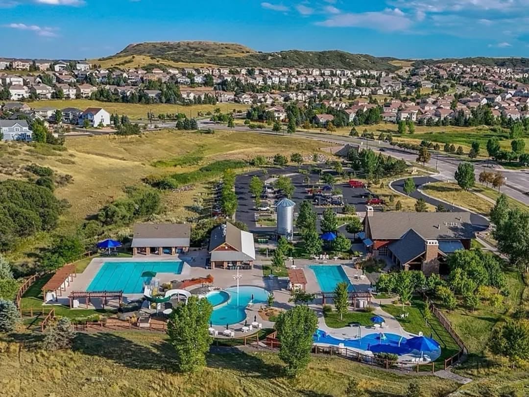 Family enjoying resort-style pool at The Meadows community in Castle Rock, CO, with lounge chairs and mountain backdrop.