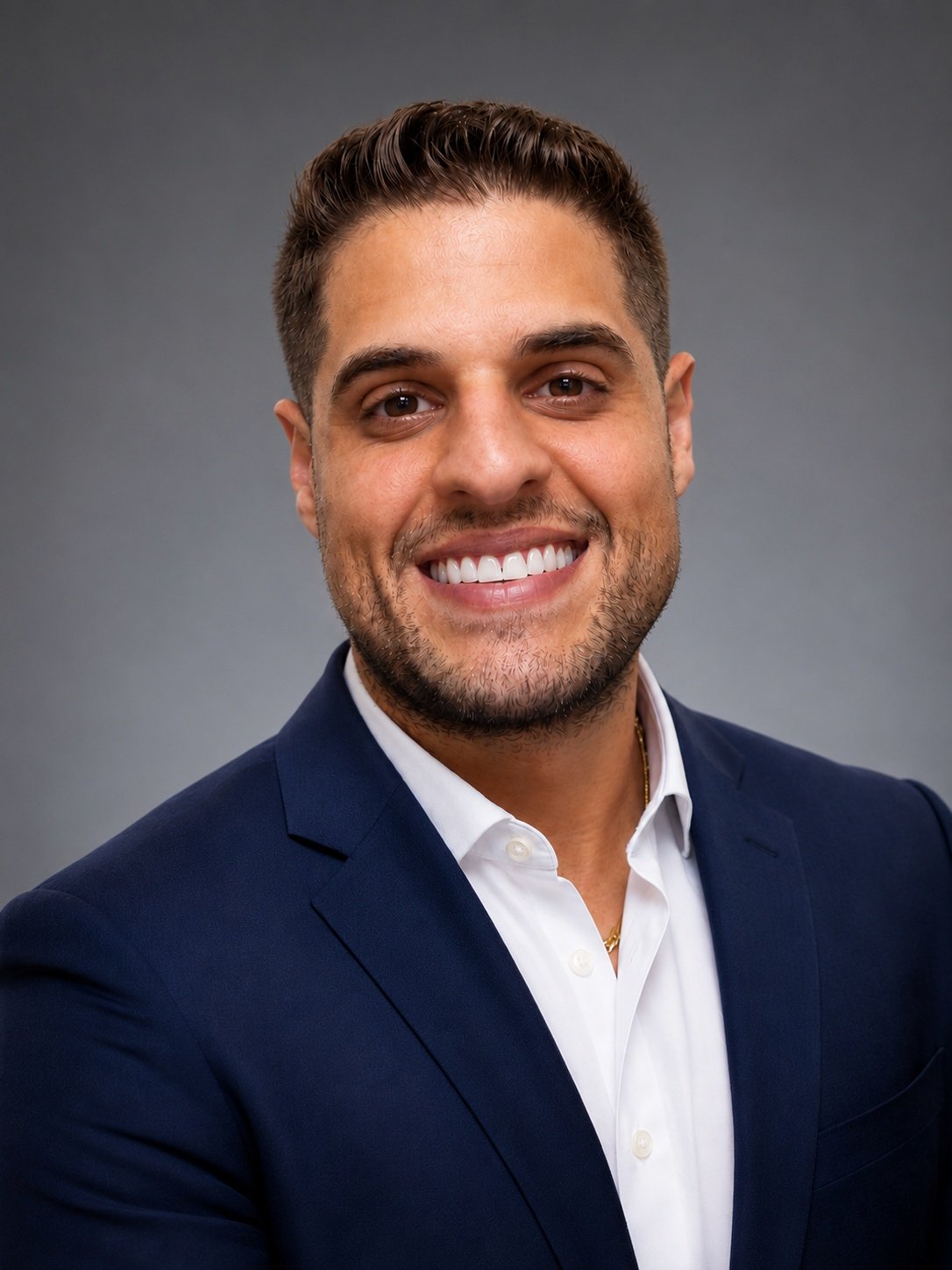 Anthony Lezza smiling in a navy suit jacket and white shirt.