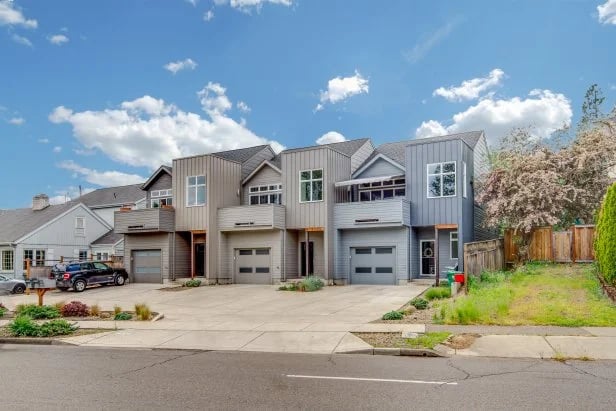 Modern attached townhouses with gray siding, garage doors, and paved driveways.