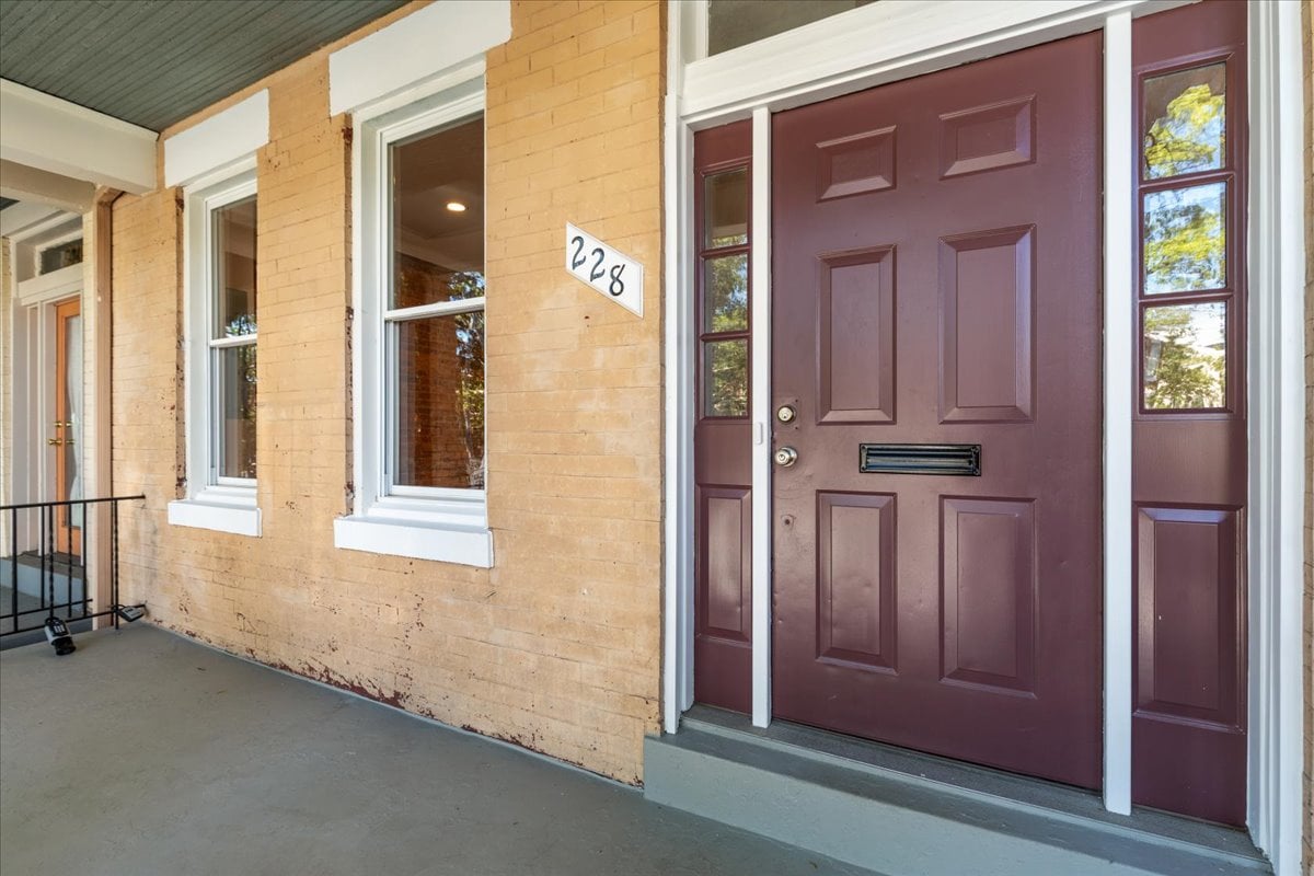 Front entrance with a burgundy paneled door, sidelights, and 228 address plaque.