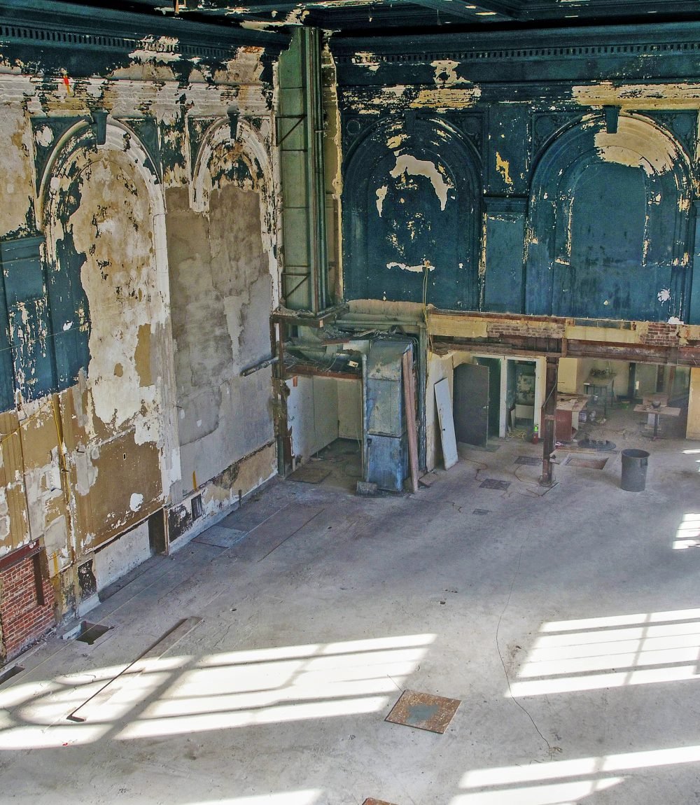 Unfinished interior with ornate arched walls, exposed utilities, and sunlight across the concrete floor.