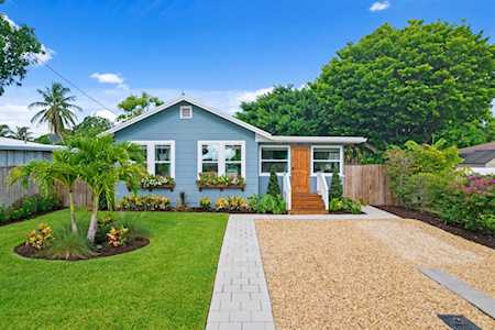 Light blue single-story house with flower boxes, a gravel driveway, and a landscaped front lawn.