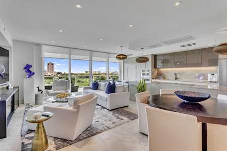 Open-plan living room and kitchen with floor-to-ceiling windows and pale contemporary furnishings.