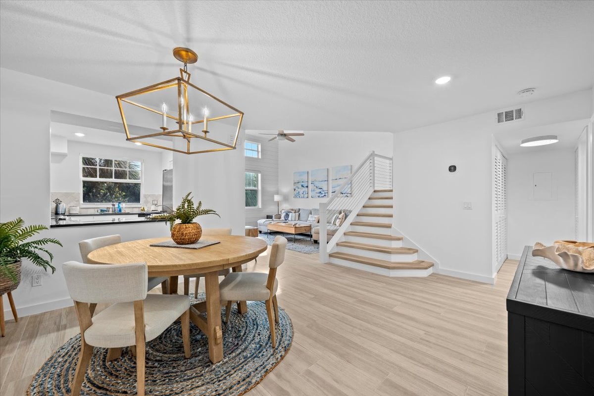 Open-plan condominium dining and living area with a round table, kitchen, and staircase.