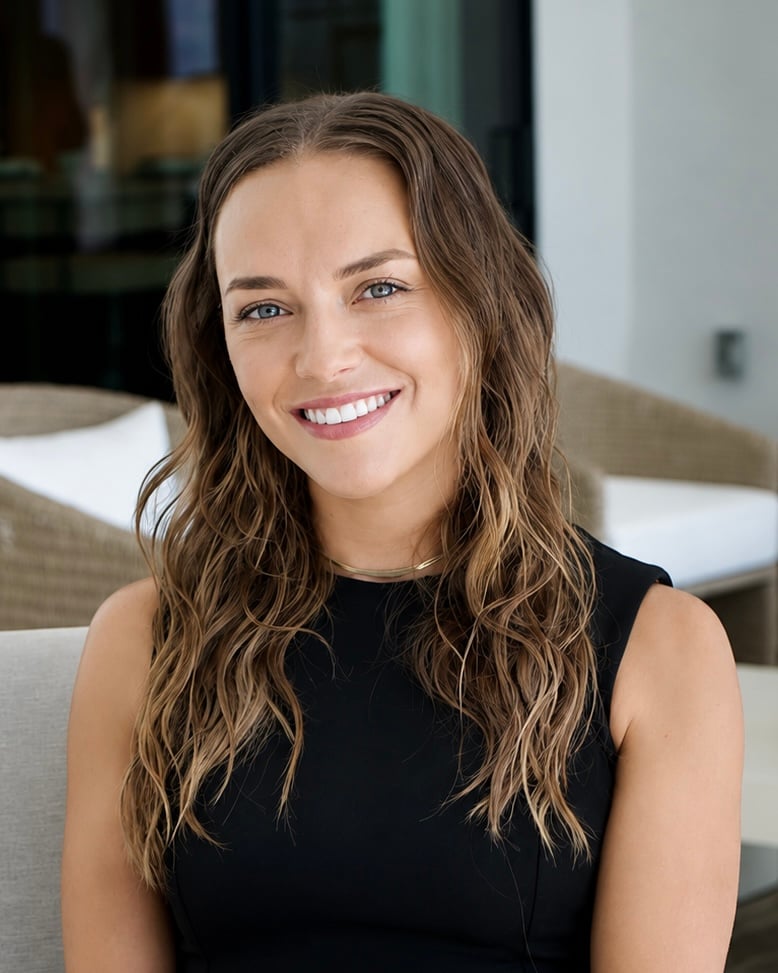 Michaela Bianca smiling in a black sleeveless top in a modern interior.