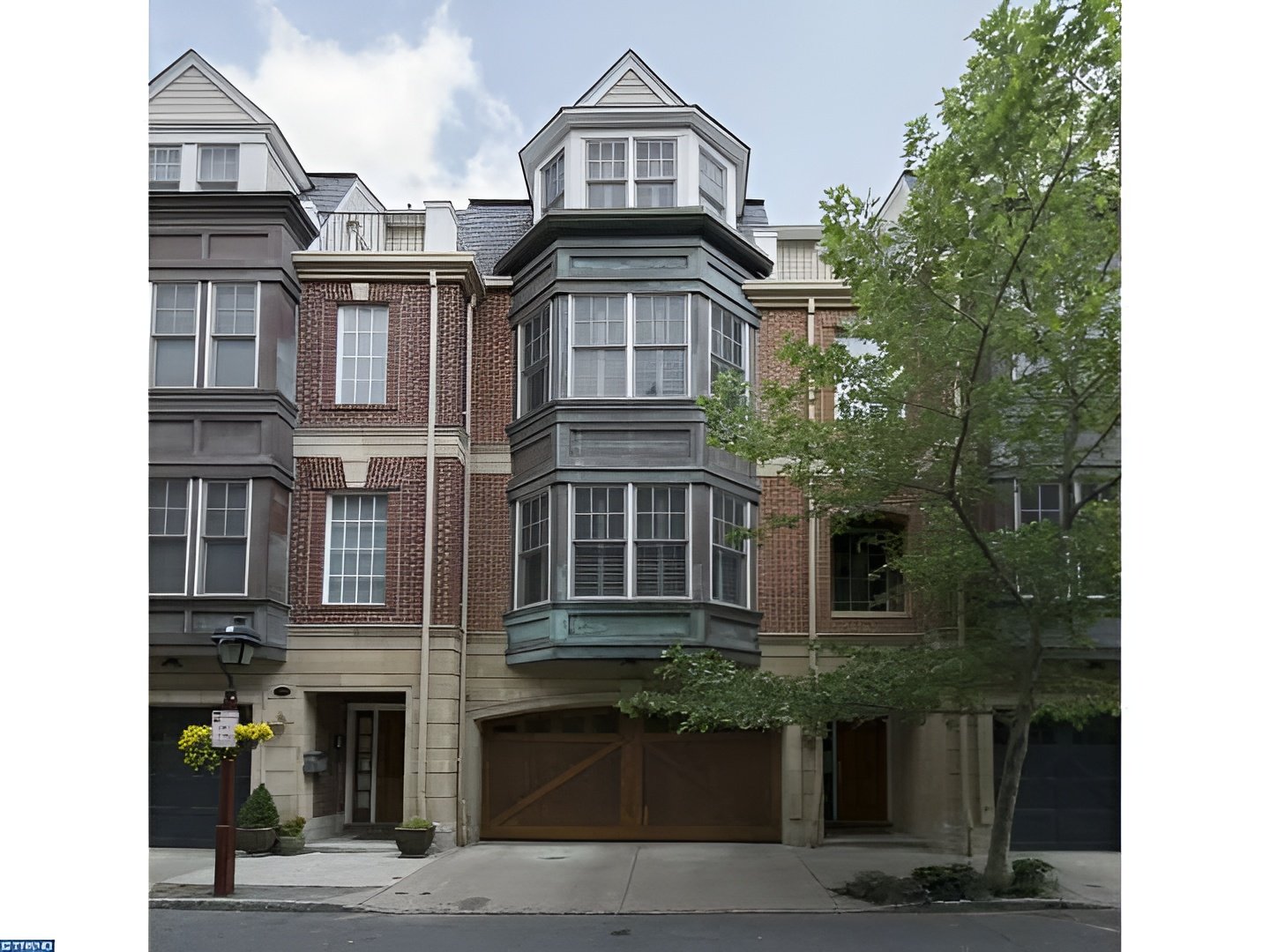 Philadelphia townhome with red brick facade, prominent bay windows, and a two-car garage.