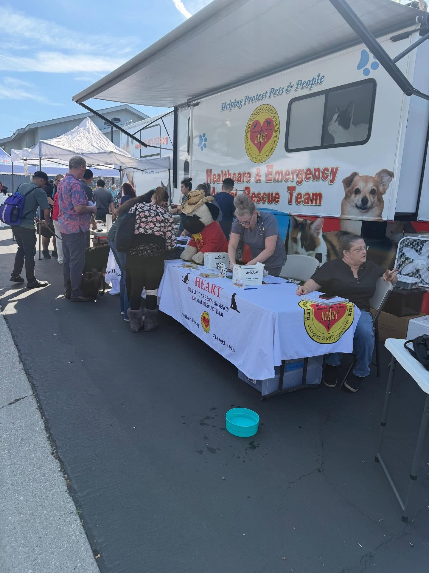 Visitors gather at an animal rescue booth with a trailer featuring dog and cat images.