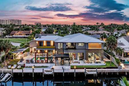 Modern two-story waterfront home with a canal dock beneath a pink and blue dusk sky.