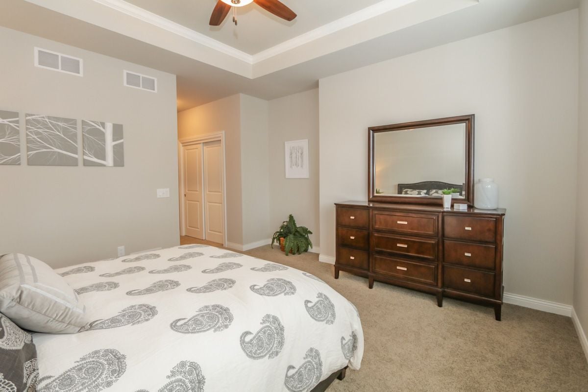 Bedroom with a paisley-covered bed and dark wood dresser beneath a large mirror.