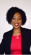 Woman with short curly hair wearing a black blazer and red top