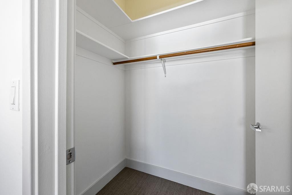 Empty white walk-in closet with built-in shelves and a wooden hanging rod.