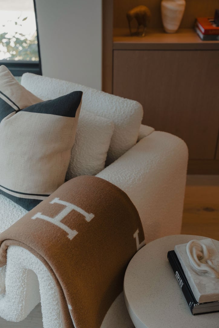 Living room with a white textured sofa, brown throw, and round side table.