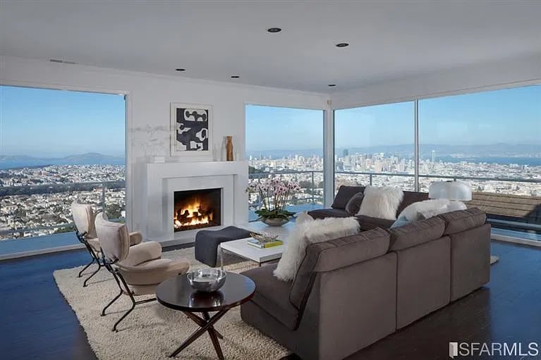 Living room with a fireplace, floor-to-ceiling windows, and sweeping city and water views.