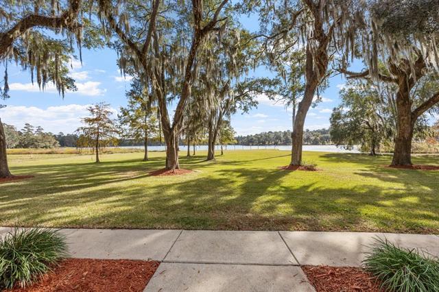 A  view of a property in 6973 McBride Pt with large, mature trees and a well-maintained lawn. The house itself is not fully visible, but the setting suggests a peaceful, scenic location.