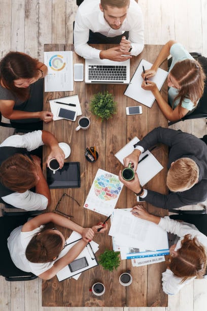  An overhead shot captures seven people seated around a rustic wooden table