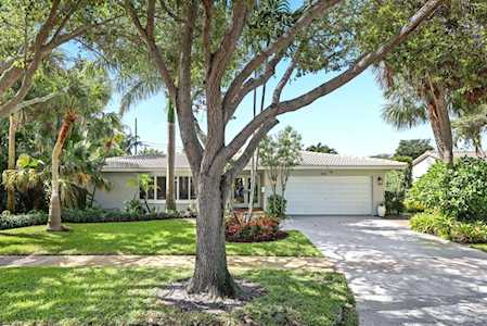 Single-story home with an attached garage, broad driveway, and a large shade tree in the front lawn.