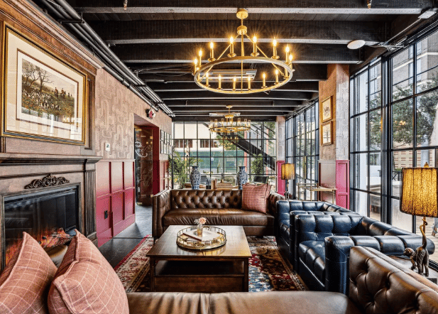 Hospitality lounge with leather sofas, a fireplace, and a brass chandelier.