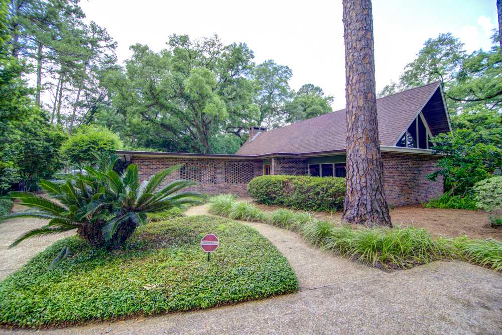A charming home featuring a large tree prominently situated in the front yard, enhancing the landscape's appeal.