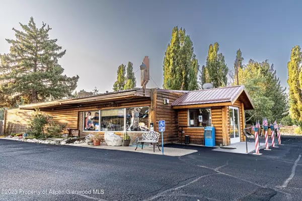 Log-sided building with a metal roof, accessible parking sign, and flags outside.