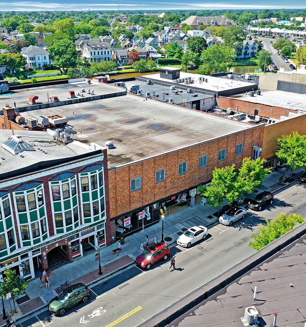 Aerial view of a brick commercial building on Cookman Avenue, with rooftop equipment and neighboring homes.