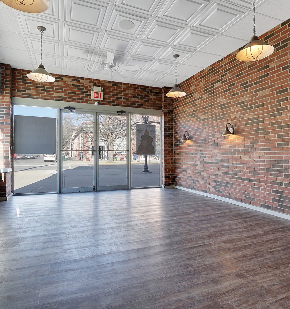 Vacant lobby with brick walls, glass entrance doors, and a white coffered ceiling.