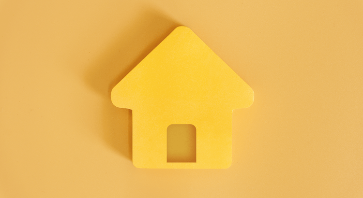 Yellow house-shaped cutout on a matching yellow background. Simple and minimalist, conveying a sense of warmth and homeliness.