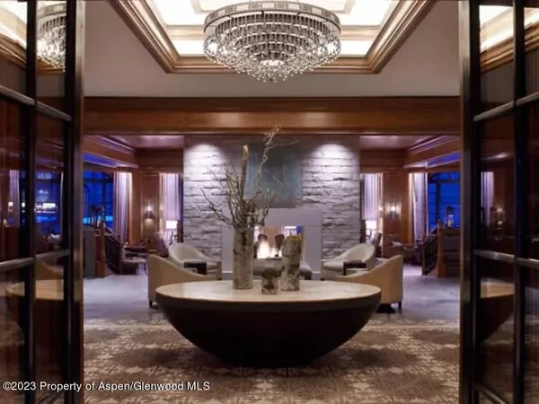 Furnished sitting area with a crystal chandelier, stone fireplace, and round table with branches.
