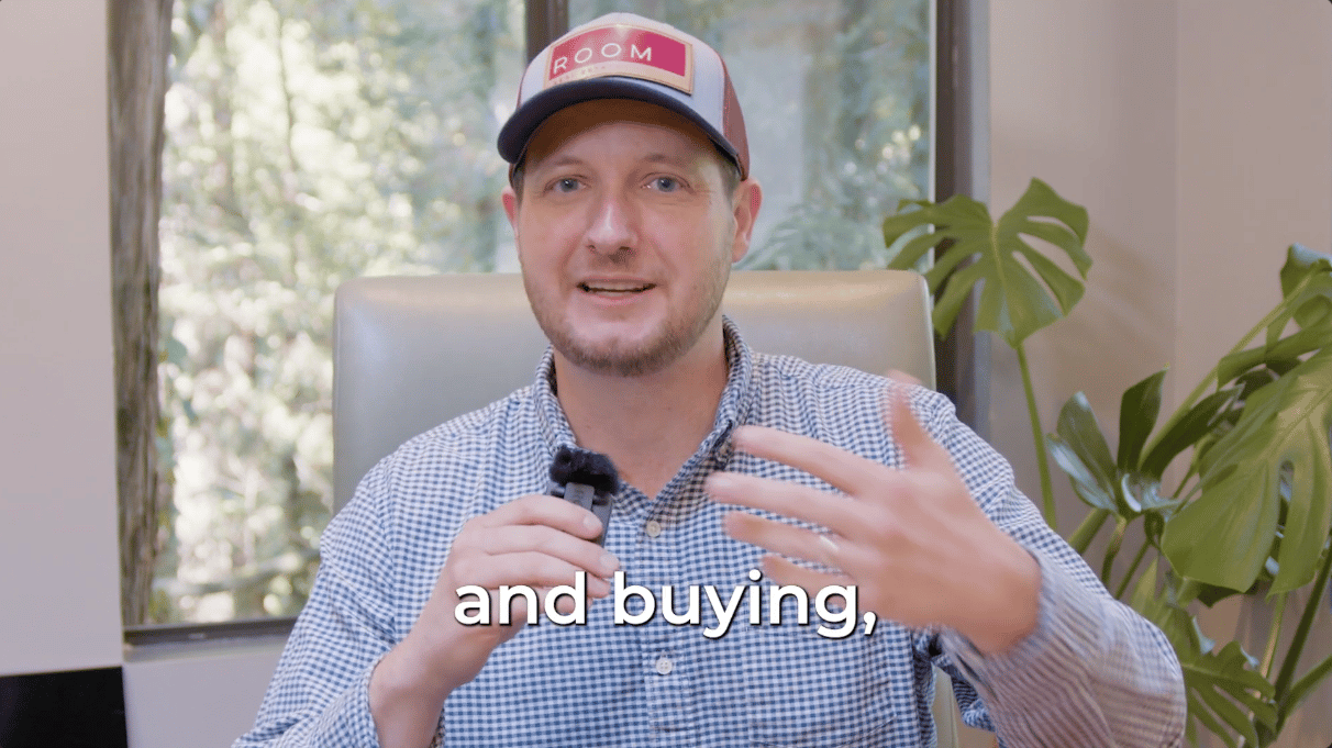 Man in a ROOM cap speaking into a microphone in a bright office.