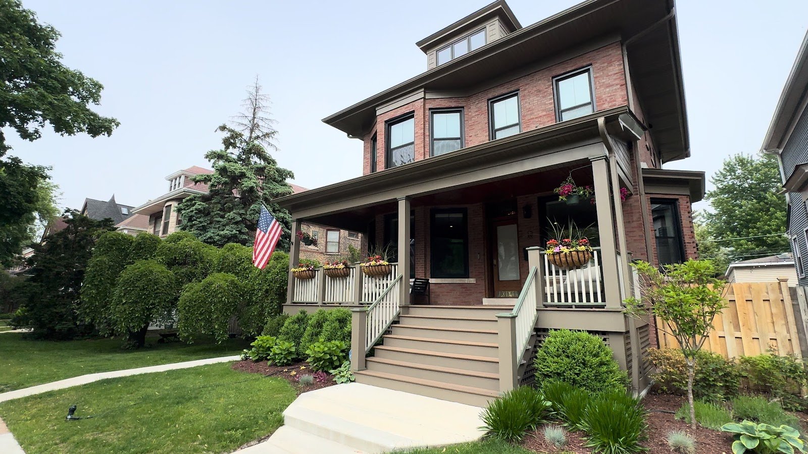 Brick house with a wide front porch and garden on a sunny Chicago street