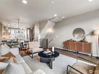 Open-plan living room with a gray sectional, round coffee table, and staircase.