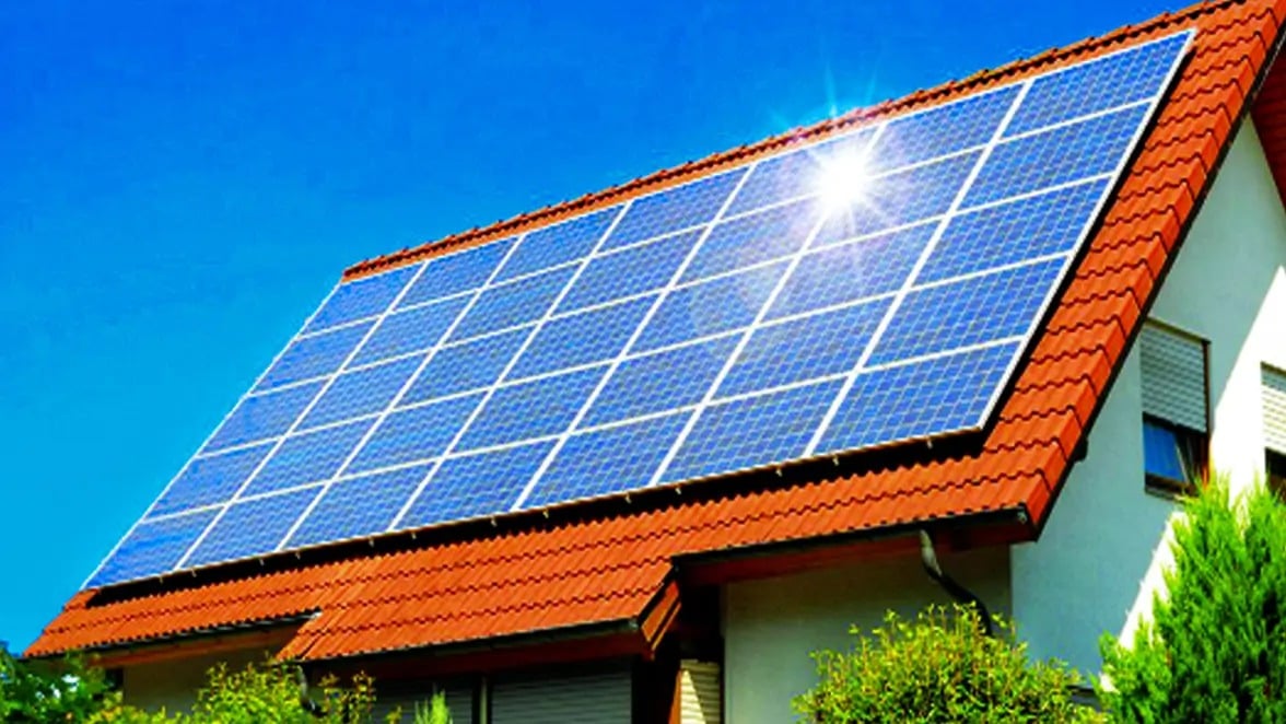 House roof covered with solar panels, with sunlight reflecting off the array.